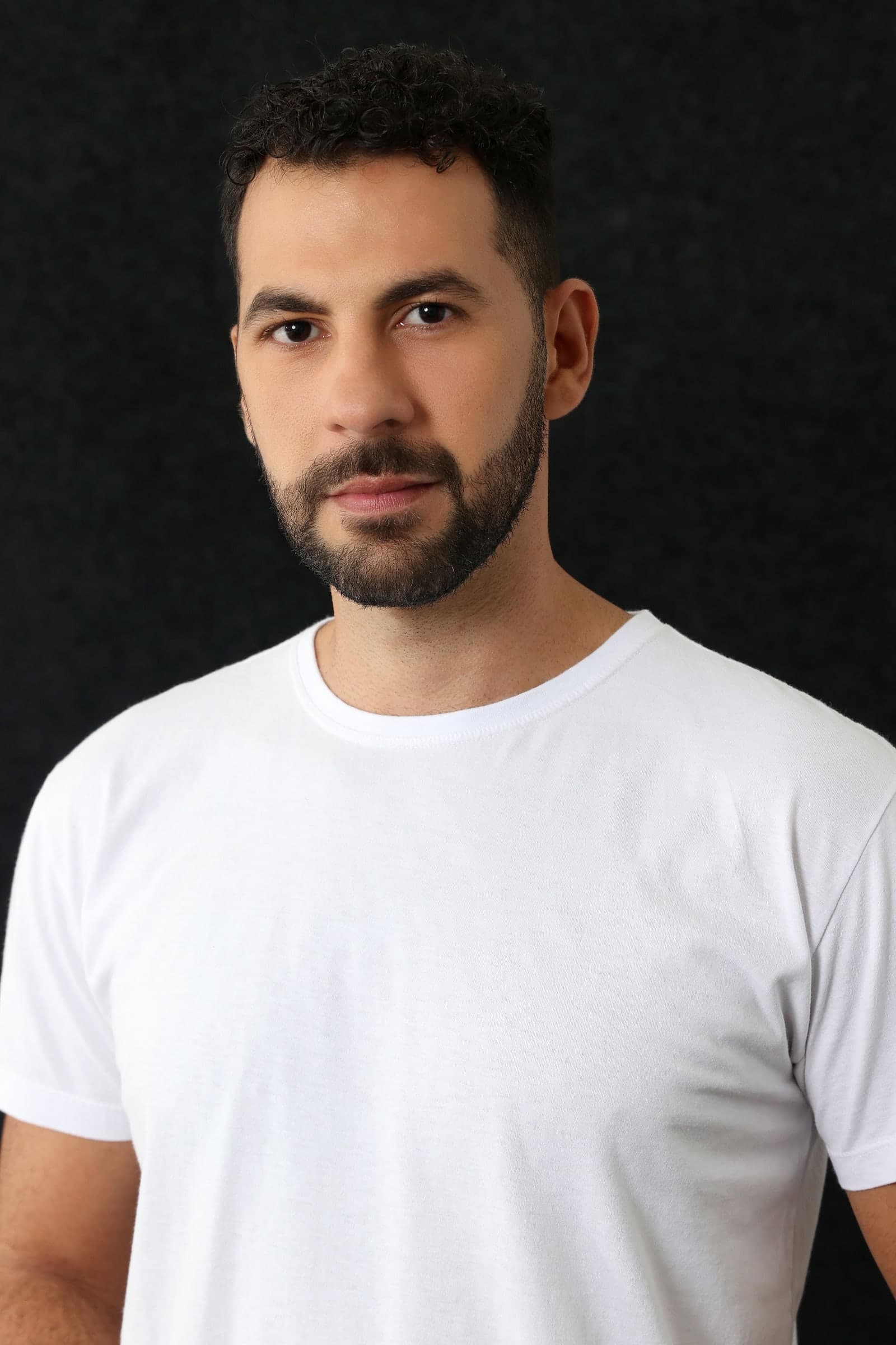 Retrato de Juraci Júnior de camiseta branca, sobre fundo preto.